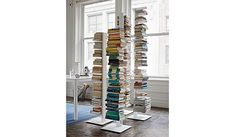 a tall stack of books sitting next to a window