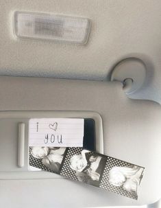 a car dashboard with two pictures and a note attached to the dash board that says i love you