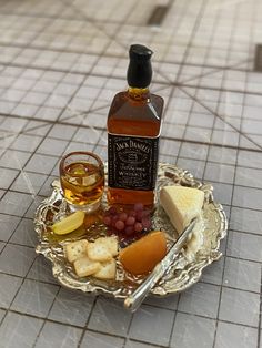 a bottle of wine, cheese and crackers on a silver plate with a spoon