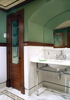 a white sink sitting under a bathroom mirror next to a wooden door in a bathroom