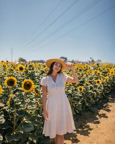 a woman in a sunflower field wearing a straw hat