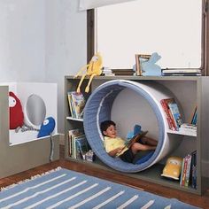 a young boy laying in a toy hammock on top of a book shelf