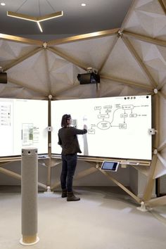 a person standing in front of two large screens with diagrams on them and an ipad next to the screen