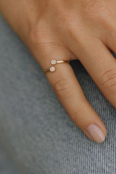 a woman's hand wearing a gold ring with three small white stones on it