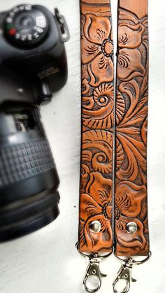 a camera strap with an intricate design on the front and side, next to a digital camera