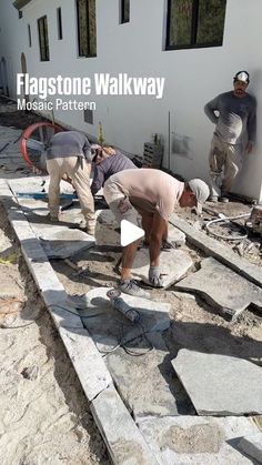 two men working on the side of a building with flagstone walk way in front of them