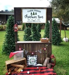 a christmas tree stand in the middle of a field with trees and decorations around it