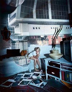 a woman sitting on the floor in front of a tv surrounded by pictures and photos