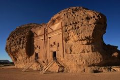 a large rock structure with steps leading to it in the middle of an arid area