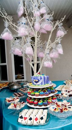 a table topped with lots of desserts and cupcakes next to a tree