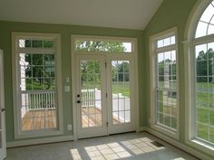 an empty room with three doors and two windows on each side of the door, in front of a grassy field