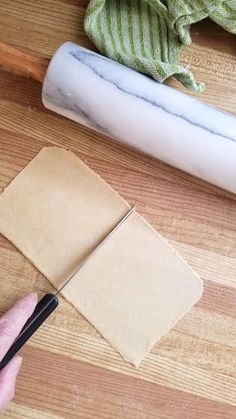 a person is cutting up some paper on a wooden table with a pair of scissors