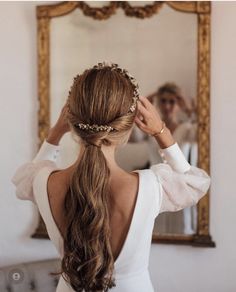 a woman with long hair in a white dress is looking at herself in the mirror