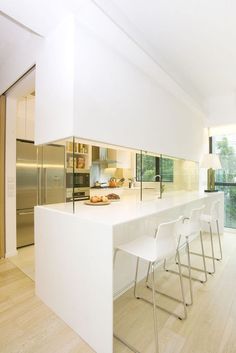 a kitchen with white counter tops and chairs