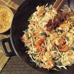 a pan filled with food and chopsticks next to a bowl of rice on a table