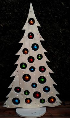 a christmas tree made out of plastic balls on a wooden surface with trees in the background