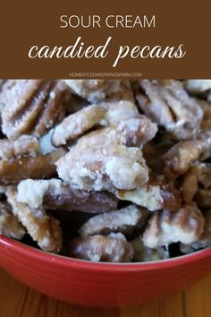 a red bowl filled with candied pecans on top of a wooden table and text overlay reads sour cream candies