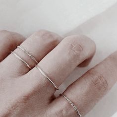 a person's hand with two thin rings on top of their fingers and the middle finger