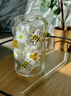 a glass with some flowers on it sitting on a table next to a potted plant