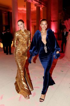 two women in gold and blue dresses walking together