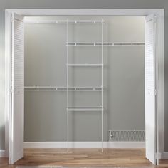 an empty closet with white shelving and wooden floors