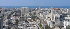 an aerial view of a city with tall buildings and the ocean in the back ground