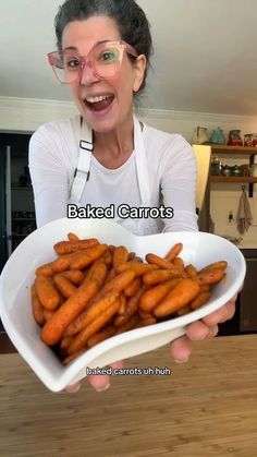 a woman holding a bowl full of carrots with the words baked carrots on it