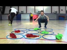 two men are playing frisbee in an indoor gym with green and blue rings on the floor