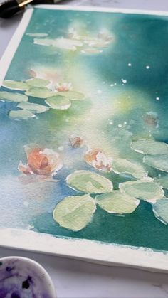 water lilies are floating on the surface of a painting with paintbrushes next to it