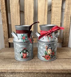 two tin canisters with christmas decorations on them sitting next to each other in front of a wooden chair