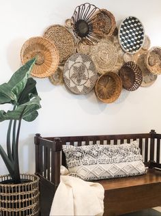 a wooden bench sitting in front of a wall with baskets hanging on it's side