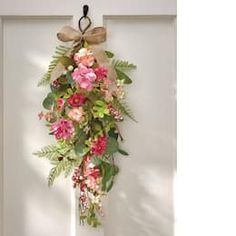 a bunch of flowers hanging from a door with a bow on it's handle