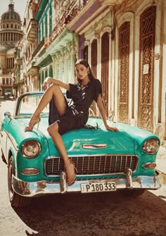 a woman sitting on the hood of an old car