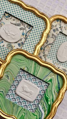 three decorative trays sitting on top of a table covered in green and white paper