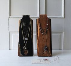 two pieces of wood with necklaces on them sitting next to each other in front of a door