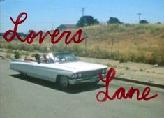 an old car is parked on the side of the road in front of a sign that says lovers lane