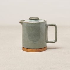 a ceramic teapot with a wooden handle on a white tableclothed surface, ready to be used as a coffee pot