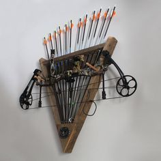 a wall mounted archery rack with arrows and bows on it's back, holding various items