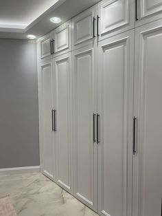 an empty room with white cabinets and marble flooring on the walls, along with gray walls