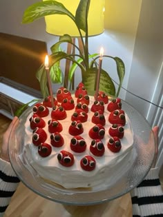 a person holding a cake with candles in the shape of eyeballs on it,