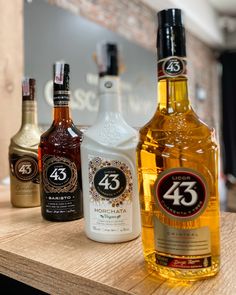 three bottles of alcohol sitting on top of a wooden table