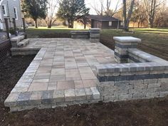 a brick patio in the middle of a yard