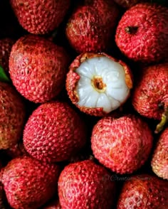 a pile of strawberries with one piece cut open