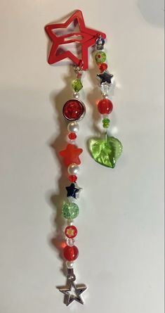 a red star hanging from the side of a wall with beads and charms attached to it