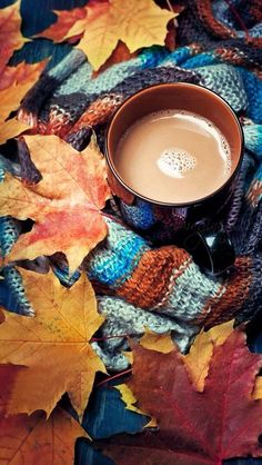 a cup of coffee sitting on top of a pile of leaves with the words good morning