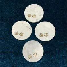 four white marble coasters with gold paw prints