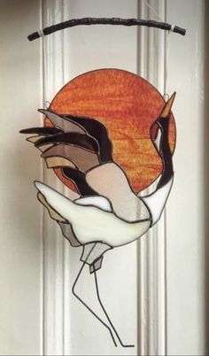 a stained glass sun catcher hanging on the front door with an image of a bird in flight