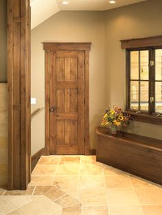 an empty room with a wooden door and window sill in the corner, next to a tiled floor