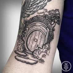 a man's arm with a black and white tattoo design on it, depicting a hobbot door