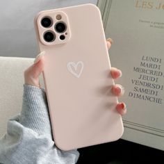 a person holding up a pink phone case with a heart sticker on it